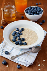 Healthy breakfast of oatmeal porridge, berries, honey and juice