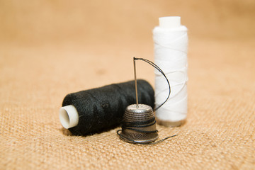 Needle, thimble and thread spool on the old cloth