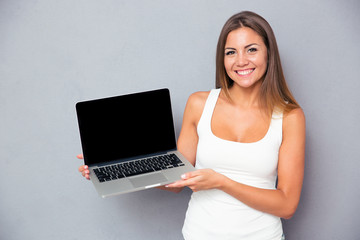 Happy girl showing blank laptop screen