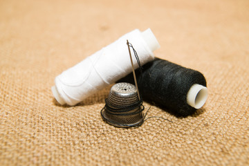 Needle, thimble and thread spool on the old cloth
