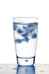 Blue tinted ice cubes in glass of water
