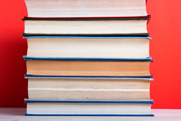 old hardback books, diary, fanned pages on red background