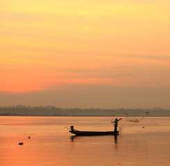 Naklejka premium fishmonger in his traditional boat at sunrise