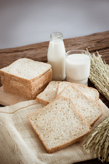 glass of milk and whole wheat bread on the wooden board