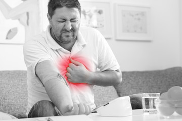 Man measuring his blood pressure and feeling chest pain. Black and white, chest highlighted with...