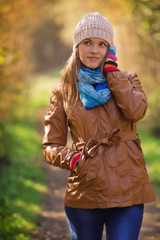 Young women walking in the forest with warm, autumn fashioned clothes