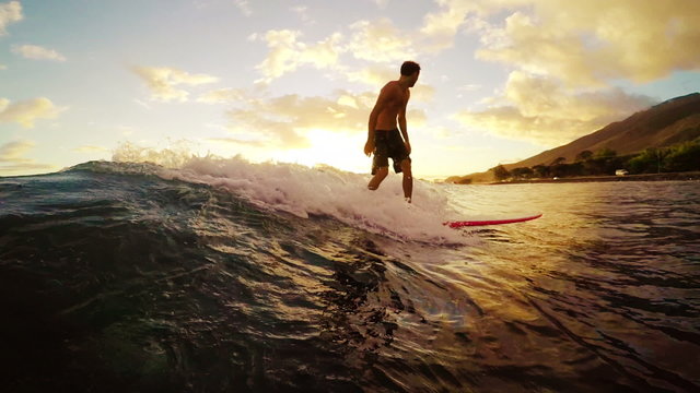 Young Man Surfing a Longboard Down The Line Away From the Camera Through a Golden Sunset in Hawaii in Slow Motion