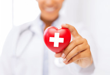 female doctor holding heart with red cross symbol