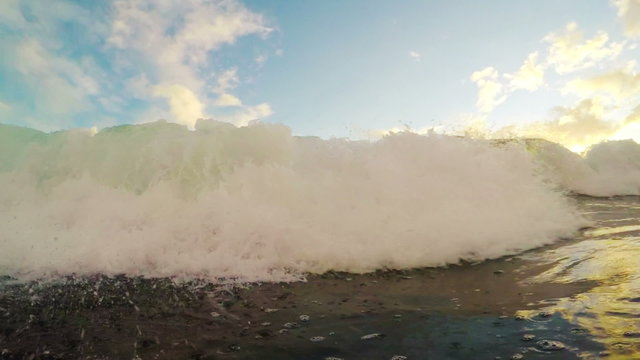 Ocean Wave Crashes and Rolls Towards the Camera During a Golden Sunset in Slow Motion