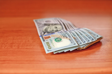 Stacks of new one hundred dollars banknotes on wooden desk. Macr