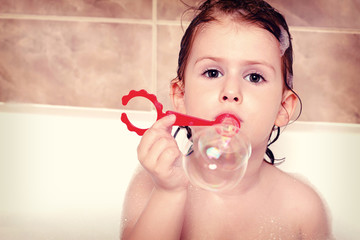 little girl playing with soap bubbles in bathtub © innafphotography