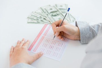 close up of hands with lottery ticket and money © Syda Productions
