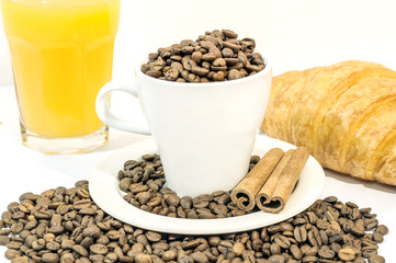 Cup of coffee filed with coffee beans with croissants and orange
