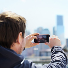 Fototapeta premium Tourist taking mobile photo of skyscrapers
