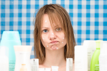 Portrait of upset cute girl with problem face skin in bathroom