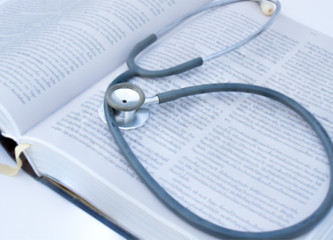 Stethoscope old put on a thick textbook content in a blur.