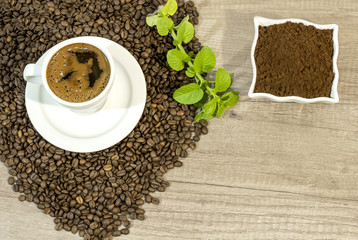 Cup of fresh coffee, coffee beans,  fresh ground coffee and mint
