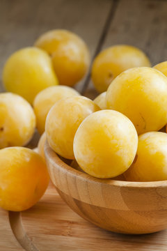 Ripe juicy yellow plums in a wooden bowl, selective focus