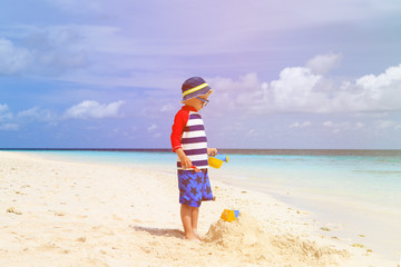 little boy building sandcastle on tropical beach