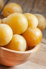 Ripe juicy yellow plums in a wooden bowl, selective focus