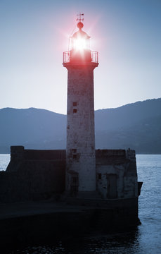 Old lighthouse tower silhouette with red light
