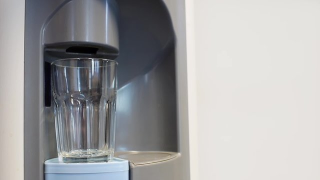 Filling big glass in water dispenser.