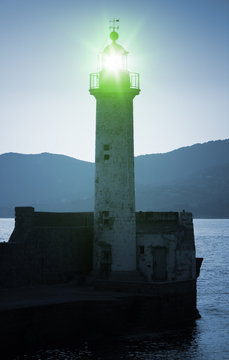 Old lighthouse tower silhouette with green light