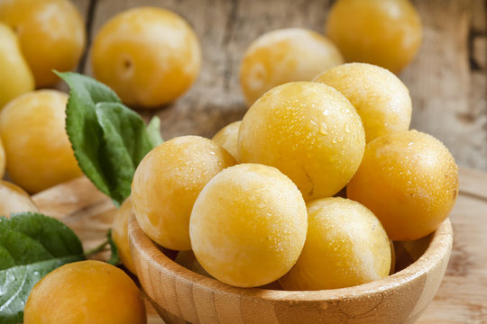 Ripe juicy yellow plums in a wooden bowl, selective focus