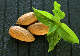 Almond nuts and green mint leaf close up.