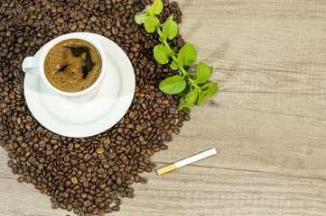 Cup of fresh coffee, coffee beans, cigar and mint tea flovers on