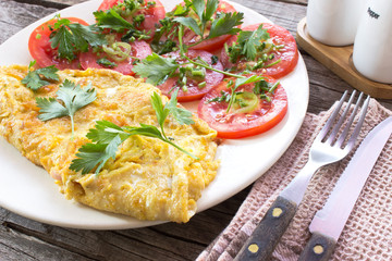 Omelette with vegetables on wooden background
