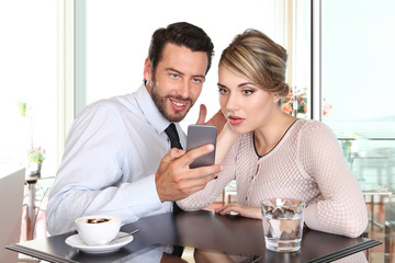 surprised happy couple looking the smartphone at the bar