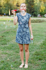 Fototapeta premium Beautiful girl in the park with soap bubbles.