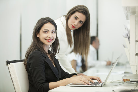 Due belle e giovani impiegate lavorano al pc in ufficio