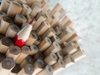 Close-up of identical graphite pencils and one red leading crayon