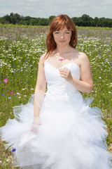 Fototapeta na wymiar Young bride walking on the flower meadow