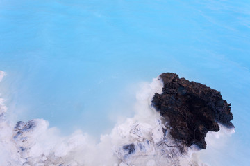 Milky white and blue water between the lava stones covered with covered with moss just outside the...