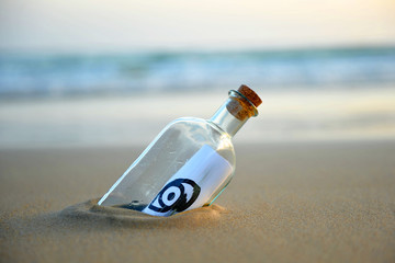 Bottle with message on the beach, all seeing eye