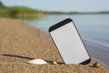 Smartphone sticking out of the sand on the beach