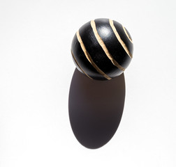 Painted wooden ball with cast shadow over white background