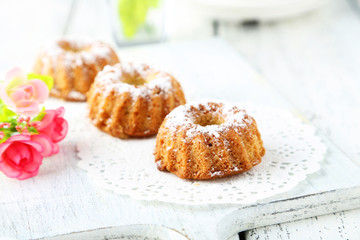 Bundt cakes on cutting board on white wooden background