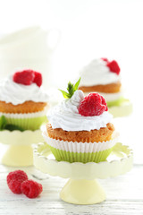 Raspberry cupcakes on cake stand on white wooden background