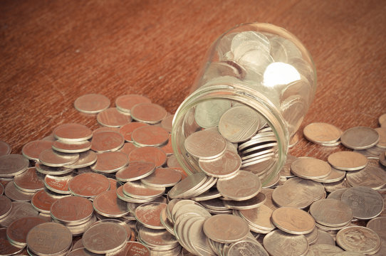 Coins spilling out of a glass bottle with filter effect retro vi