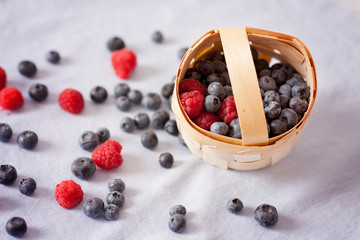 Fresh blueberries and raspberries in a basket on a blue  backgro