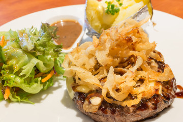 Beef steak serve with cheese , onion and potato
