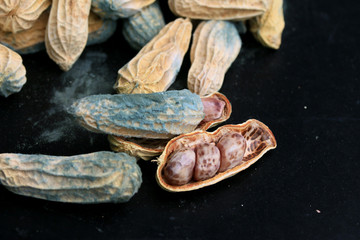 heap of moldy peanuts on a black background