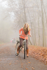 Active woman riding bike in autumn park.