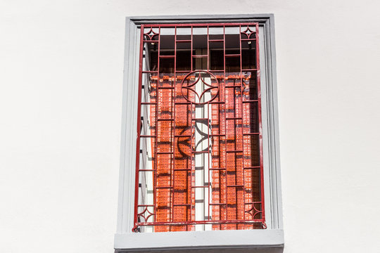 Red iron grating on grey square window