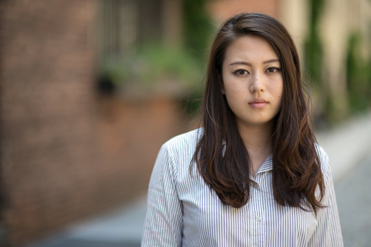 Young Asian woman in city smile happy calm face portrait