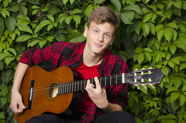 Portrait of beautiful teenager playing guitar outside